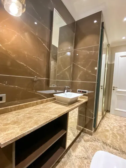 A look inside the bathroom at C-926. The rich brown marble, mirrored cabinet doors, and sleek vanity create a space that is both functional and highly luxurious.