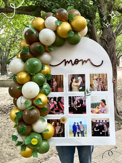 A Mother's Day memory board, decorated with an earthy-toned balloon arch and featuring a grid of family photos.