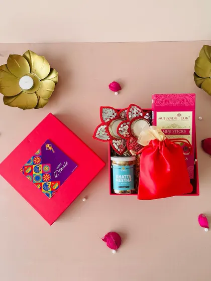 This red combo box is a perfect example of a complete gift under ₹1000, including diyas, snacks, and a potli bag.