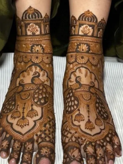 A close-up of a beautiful foot design featuring peacocks and hanging jhumka (earring) motifs.