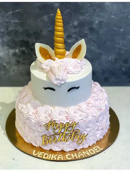 A beautiful two-tiered unicorn cake featuring delicate pink rosettes and a golden horn. This is one of our most popular designs for unicorn-themed birthday parties.