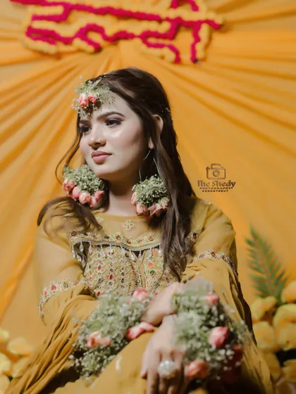 A lovely seated portrait of bride Simran against a vibrant yellow backdrop. Her thoughtful expression and beautiful attire make for a timeless Haldi photo.