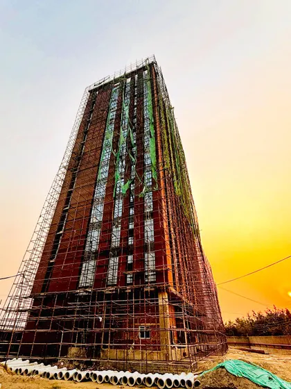 An office tower under construction, captured at sunset. The scaffolding reveals the underlying structure and the methodical application of the exposed brick facade, which gives the building its distinct character even before completion.