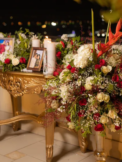 A memory table set up for an anniversary. I used an ornate golden console table to display framed photos of the couple, surrounded by romantic floral arrangements and candles.