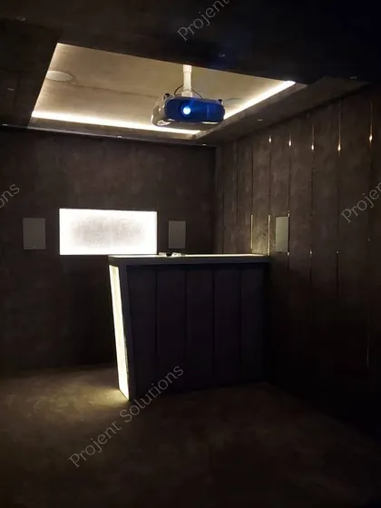A low-light shot capturing the mood of a theater room before the movie begins, focusing on the bar and accent lighting.