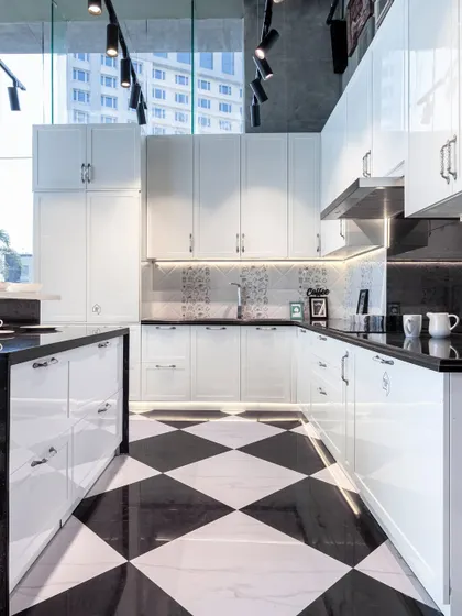 This stunning black and white kitchen showcases a classic checkerboard floor, high-gloss white cabinets, and a spacious island, creating a look of timeless sophistication.