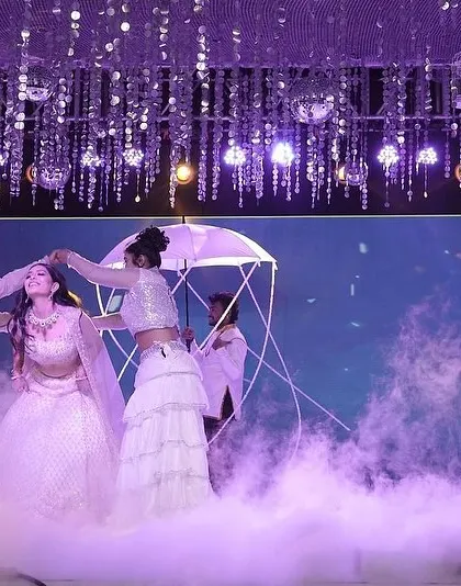 A dreamy moment from a bridal solo, where backup dancers use a prop umbrella to frame the bride beautifully amidst a cloud of smoke.