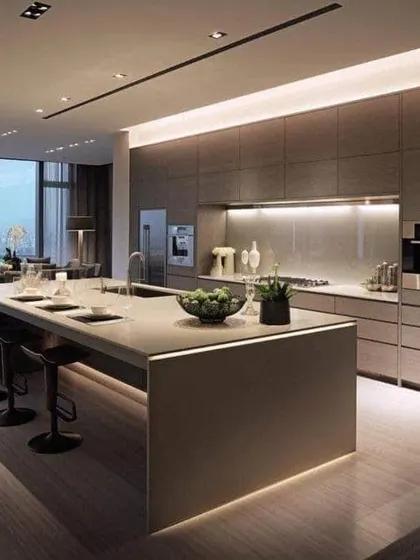 This spacious open-concept kitchen features a large island with seating, making it the heart of the home. The dark, flat-panel cabinets and integrated lighting give it a sleek, high-end feel.