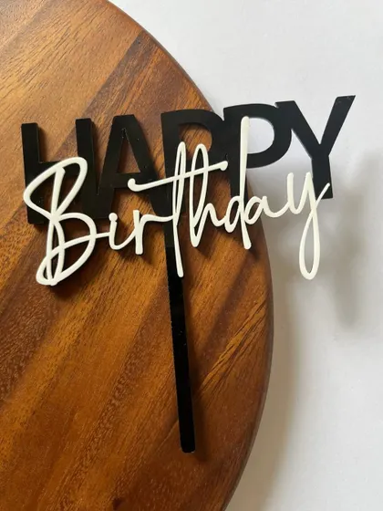 A modern layered acrylic "Happy Birthday" topper. The combination of bold black block letters and a delicate white script creates a stylish contrast.
