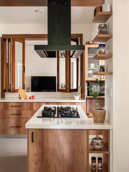 A detail of the kitchen island, showing how the pre-existing column was used to create ledges for spice storage. The natural teak laminate on the shutters adds warmth and simplicity.