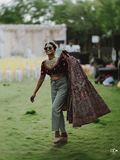 A duplicate of the full-length shot of the bride in jeans carrying her lehenga.