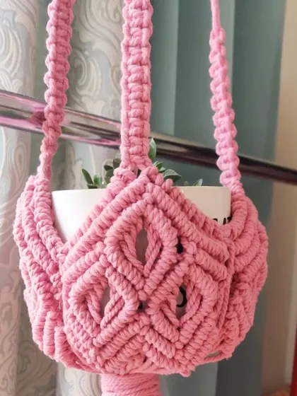 A close-up of a lovely pink plant hanger with a diamond-patterned basket.