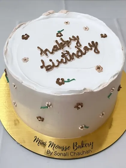 Handcrafted with love. This minimalist cake features delicate, hand-piped brown flowers for a rustic and charming birthday celebration.