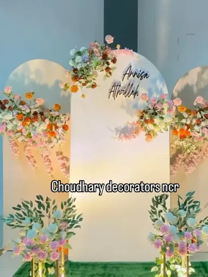 An elegant and modern backdrop ideal for an engagement, roka, or sagan ceremony. The setup features three white arched panels decorated with beautiful pastel and bright floral arrangements and personalized with the couple's names.