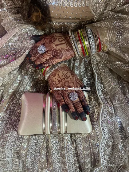 A beautiful shot of the bride's hands with her rings and clutch, showing how the mehendi complements her entire look.
