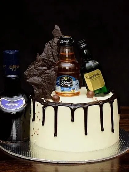 A sophisticated drip cake for a whiskey connoisseur. This design is topped with miniatures of Antiquity, Black & Milds, and Signature, complete with a dark chocolate sail for extra drama.
