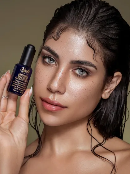 A confident portrait of the model holding the skincare product. Her direct gaze and healthy, glowing skin serve as a powerful testimonial to the product's efficacy. The styling is minimal to ensure the focus remains on the natural beauty of the skin and the product itself.
