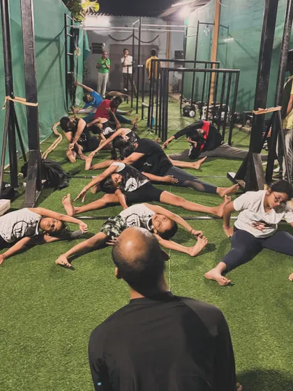 A coach leading the class in a side split stretch. We guide our members to push their limits safely.