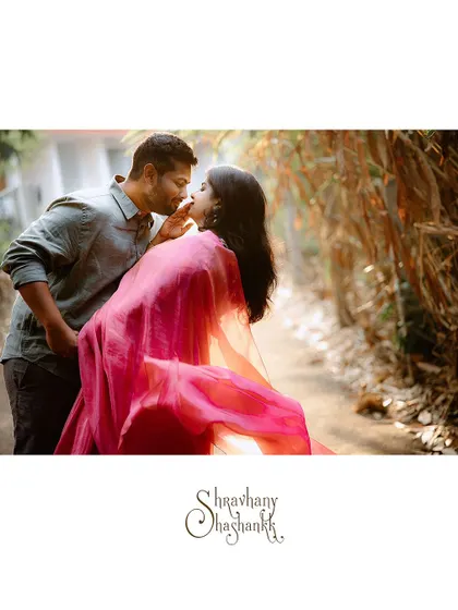 A cinematic shot of a couple about to kiss, the bride's flowing pink saree adding a splash of color.