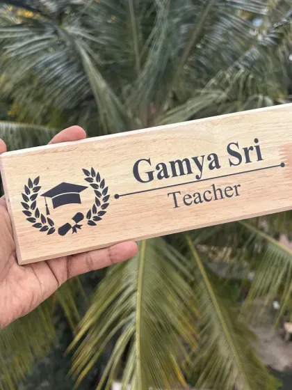 A personalized wooden nameplate for a teacher, featuring a graduation cap emblem. It's a thoughtful gift for Teacher's Day.