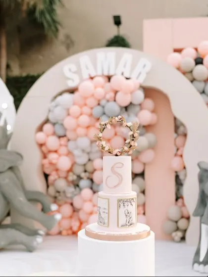 The beautiful birthday cake, perfectly themed with a gold wreath and the birthday boy's initial, set against the stunning balloon backdrop.