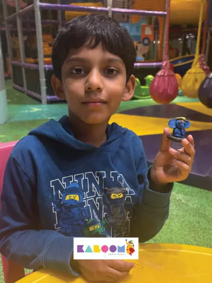 A young boy proudly holds up his handmade blue clay Ganesha, a result of his focus and creativity during our special Ganesh Chaturthi event for kids.