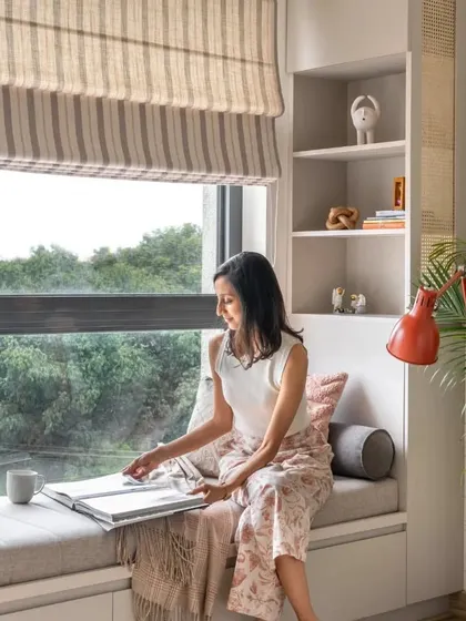 A cozy reading corner created from a bay window. The design includes a comfortable seat with storage underneath and open shelves on the side for books and decor.