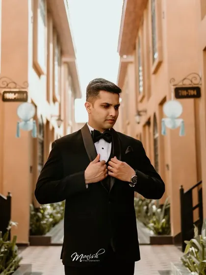 A dapper solo portrait of the groom in his classic black tuxedo, looking sharp and ready for the big moment.