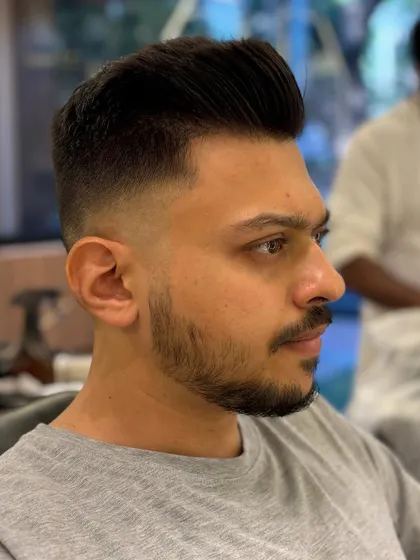 A side profile of a classic men's pompadour with a high fade. The look is sharp, clean, and effortlessly stylish.