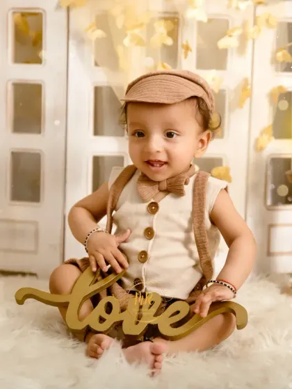 This little boy holds a "love" sign, completing the charming look of his boho-chic photoshoot.
