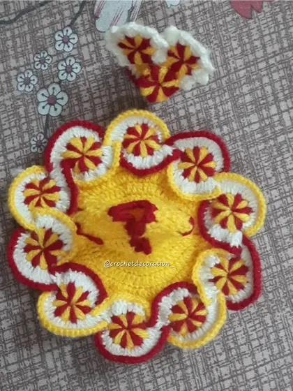 This intricate crochet poshak features a bright yellow base with red and white pinwheel designs along the scalloped edge. The detailed colorwork is also reflected in the matching heart-shaped pagdi.