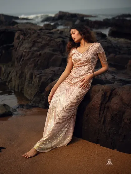 A relaxed pose, with the model leaning against a rock. The soft light and the beautiful texture of the sequined dress create a romantic and elegant beach portrait.