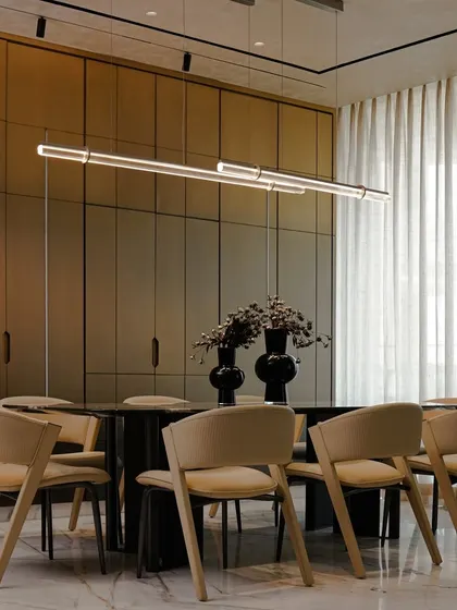 This dining area is designed for warmth and elegance, featuring soft beige chairs, a stone tabletop, and a slim pendant light. The clean, uncluttered look is maintained with hidden bar cabinetry, creating a timeless space for everyday living.