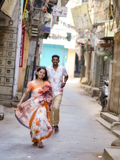 A fun, candid moment of a couple running through a narrow city lane. This captures their playful energy and the charm of the location.