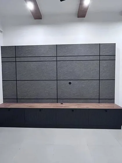 A full view of a modern TV unit with a dark grey panelled wall and a light wood console. The design is clean, minimalist, and highly functional, perfect for contemporary living.