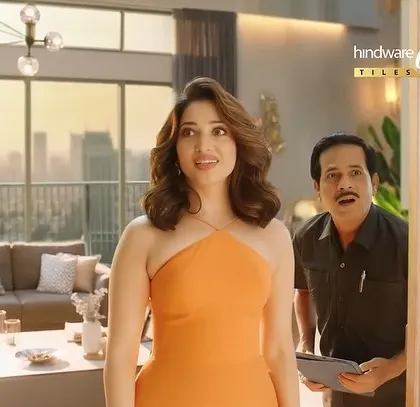 A shot of Tamannaah from the Hindware ad, looking surprised. Her bright orange dress makes her the focal point of the scene.