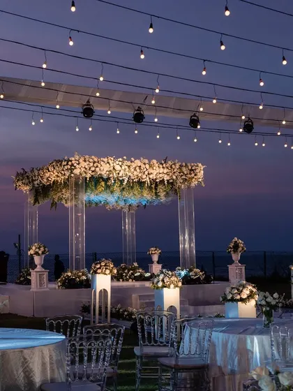 The sundowner mandap in Goa as dusk settles in. The combination of the purple sky, fairy lights, and white florals was pure magic.