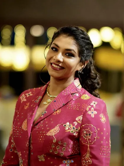 A close-up portrait highlighting the client's happy smile and the detailed embroidery of her jacket.