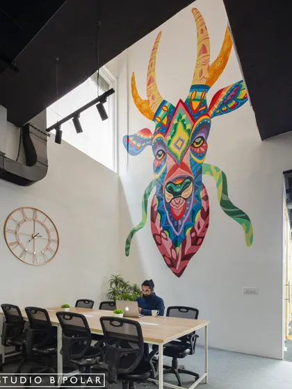 This shot highlights the scale of the custom mural, which overlooks a collaborative work table. The artwork's vibrant, tribal-inspired pattern creates a strong visual identity for the space and fosters a creative atmosphere.