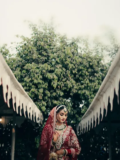 A striking portrait of the bride framed by the architecture of the venue. The symmetry of the angel-wing-like awnings creates a unique and memorable composition.