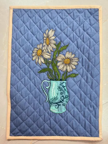 A lovely placemat with an embroidered vase of daisies, finished with diamond crosshatch quilting.