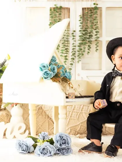 Dressed to impress in a dapper suit and hat, this little gentleman is celebrating his first birthday by the piano.