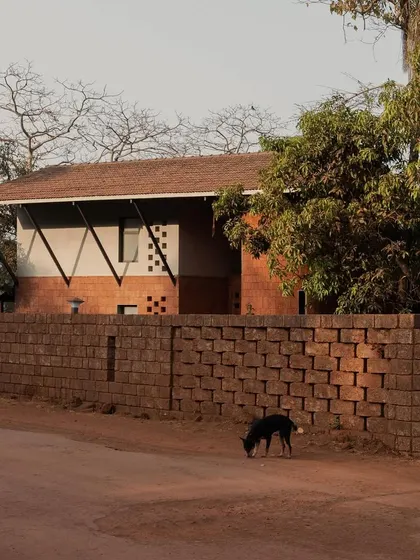 Another angle of Maison Rouge from the street, highlighting the laterite boundary wall.