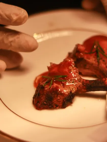 Perfectly cooked lamb chops, elegantly plated with a drizzle of sauce.