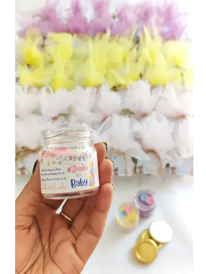 Holding a personalized mini jar candle from a baby shower order, showing the custom "#ShinkuKiBaby" sticker.