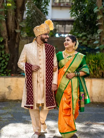 A classic walking shot of the couple, capturing their coordinated steps and happy glances, with beautiful natural light filtering through the trees.