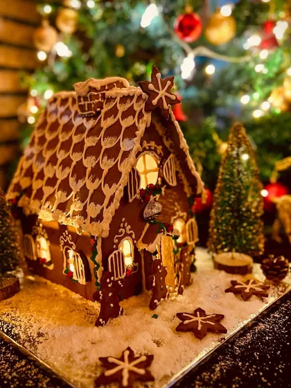 An illuminated gingerbread house from our Christmas range has scalloped roof details, icing borders and small star-shaped decorations.