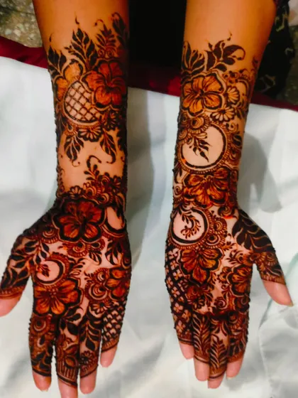 The hibiscus flower design after the henna paste has started to dry and darken, beginning the process of leaving a beautiful stain.