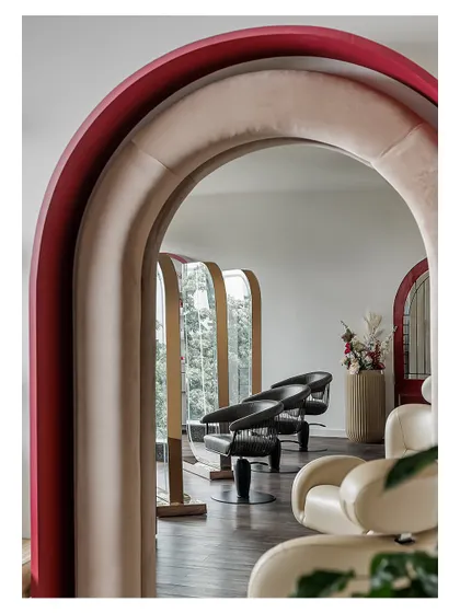 Looking through a series of layered, velvet-lined arches reveals the main styling area. This architectural feature creates a sense of depth and rhythm, guiding the eye through the space while adding a touch of drama.