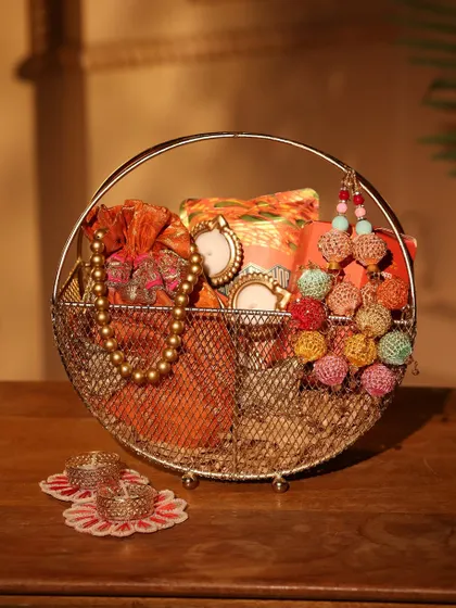 A beautiful and traditional Diwali gift basket, featuring a metal wire frame, filled with colorful potlis, mini photo frames, and decorative tassels.